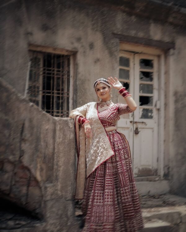 Model wearing a garnet red occasion outfit beside a heritage building