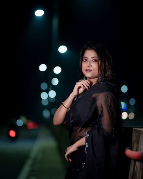 Model wearing a black saree photographed in evening light
