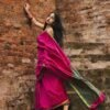 Model wearing a plum-toned saree against a brick wall