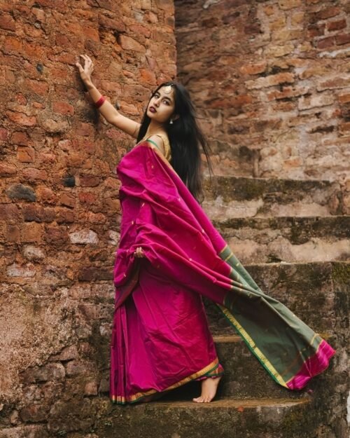 Model wearing a plum-toned saree against a brick wall