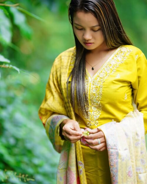 Model wearing a saffron yellow three-piece set outdoors