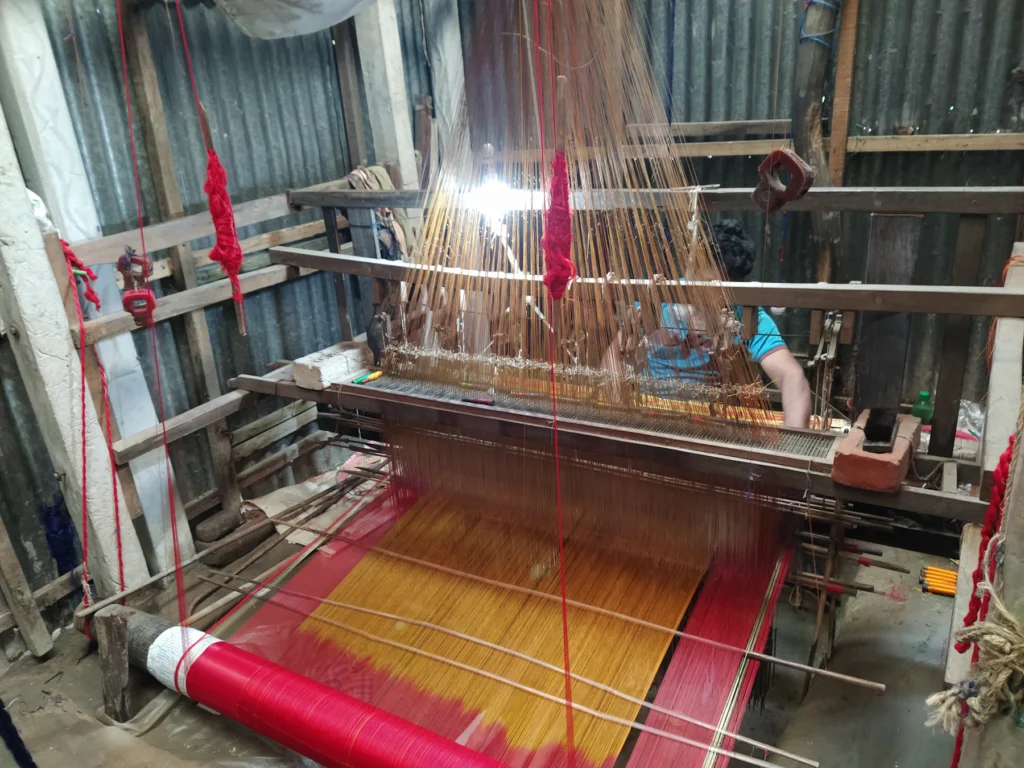 A handloom weaving a red and gold saree in Pathrail, Tangail